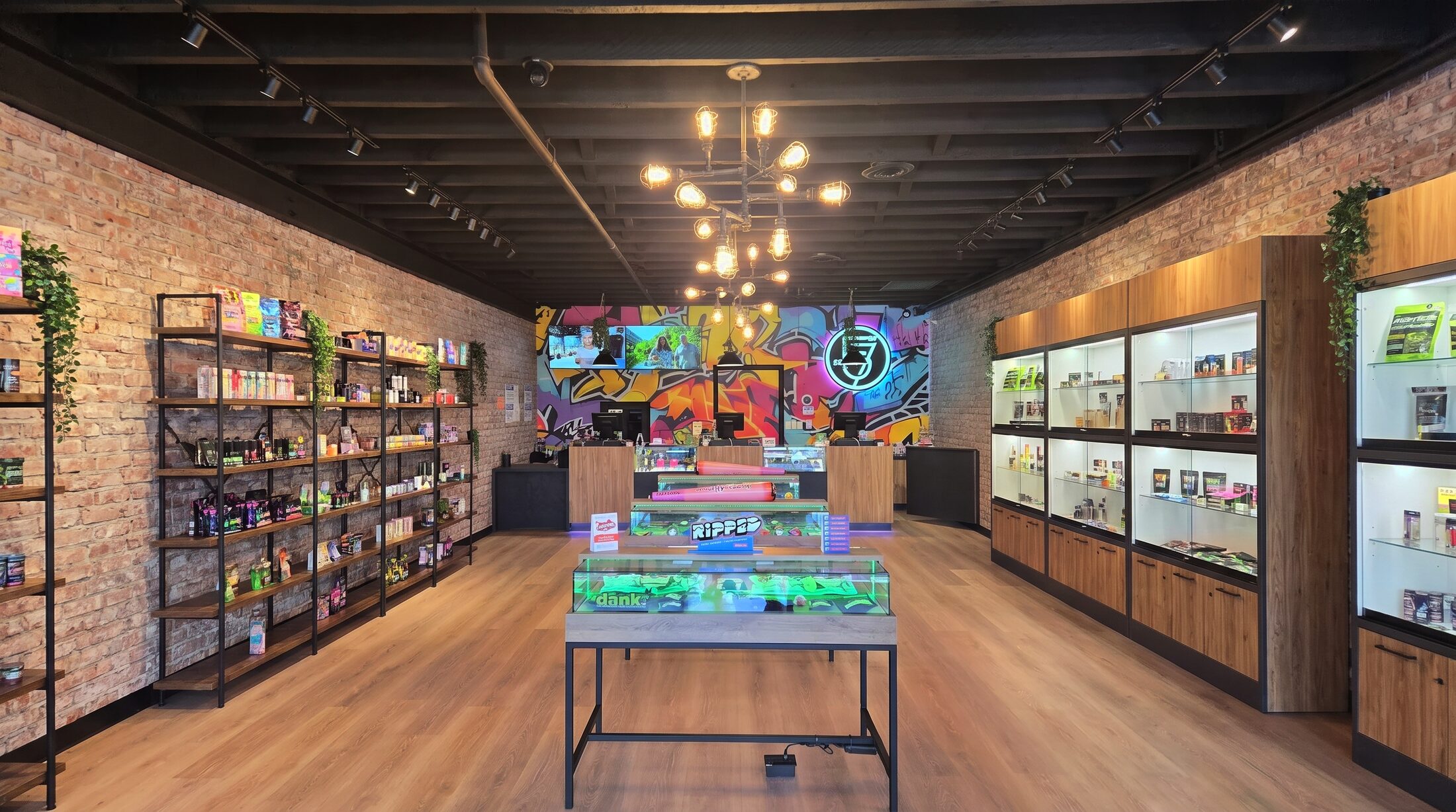 Inside Studio 57 NY at 570 Midland Avenue, Staten Island: graffiti mural, glowing neon 57 sign, Edison-bulb chandeliers and green-lit cannabis display cases